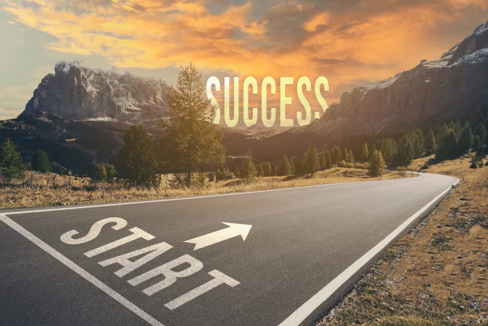 a starting line headed for a mountain range with the word success behind it